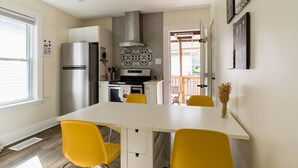 Une cuisine moderne avec un plan de travail blanc, des chaises jaunes et des appareils électroménagers en acier inoxydable.