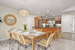 A modern kitchen with wooden cabinets, a stainless steel refrigerator, and a central island with stools.