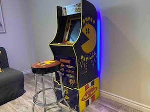 A Pac-Man arcade machine with a stool in front.