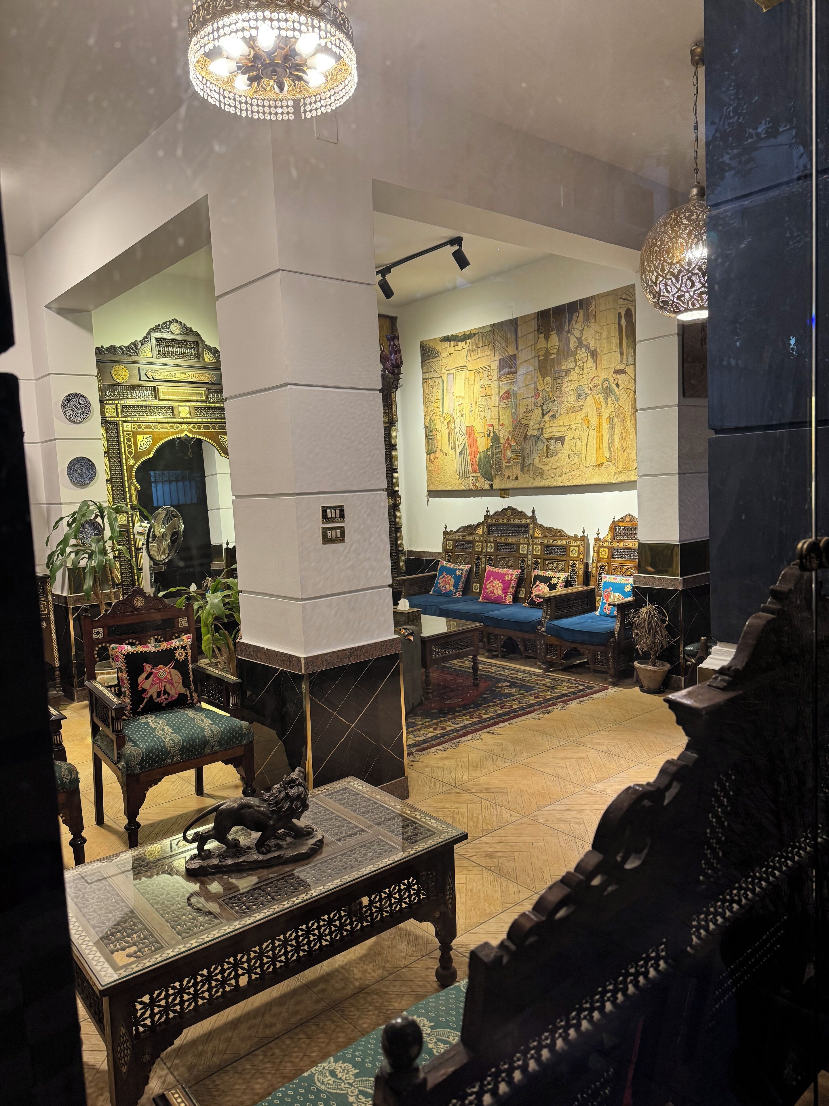 Un interior tradicional con muebles ornamentales, un mural grande y una araña.