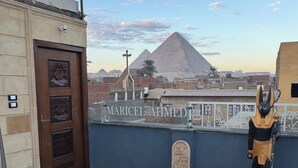 A room with a view of the pyramids, a statue, and a sign reading "MARICEL AHMED". - Osiris pyramids view inn  (Giza)