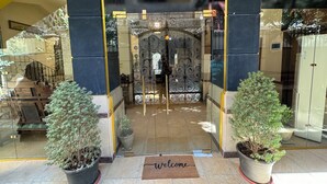 A hotel entrance with a glass door, potted plants, and a welcome mat. - Osiris pyramids view inn  (Giza)