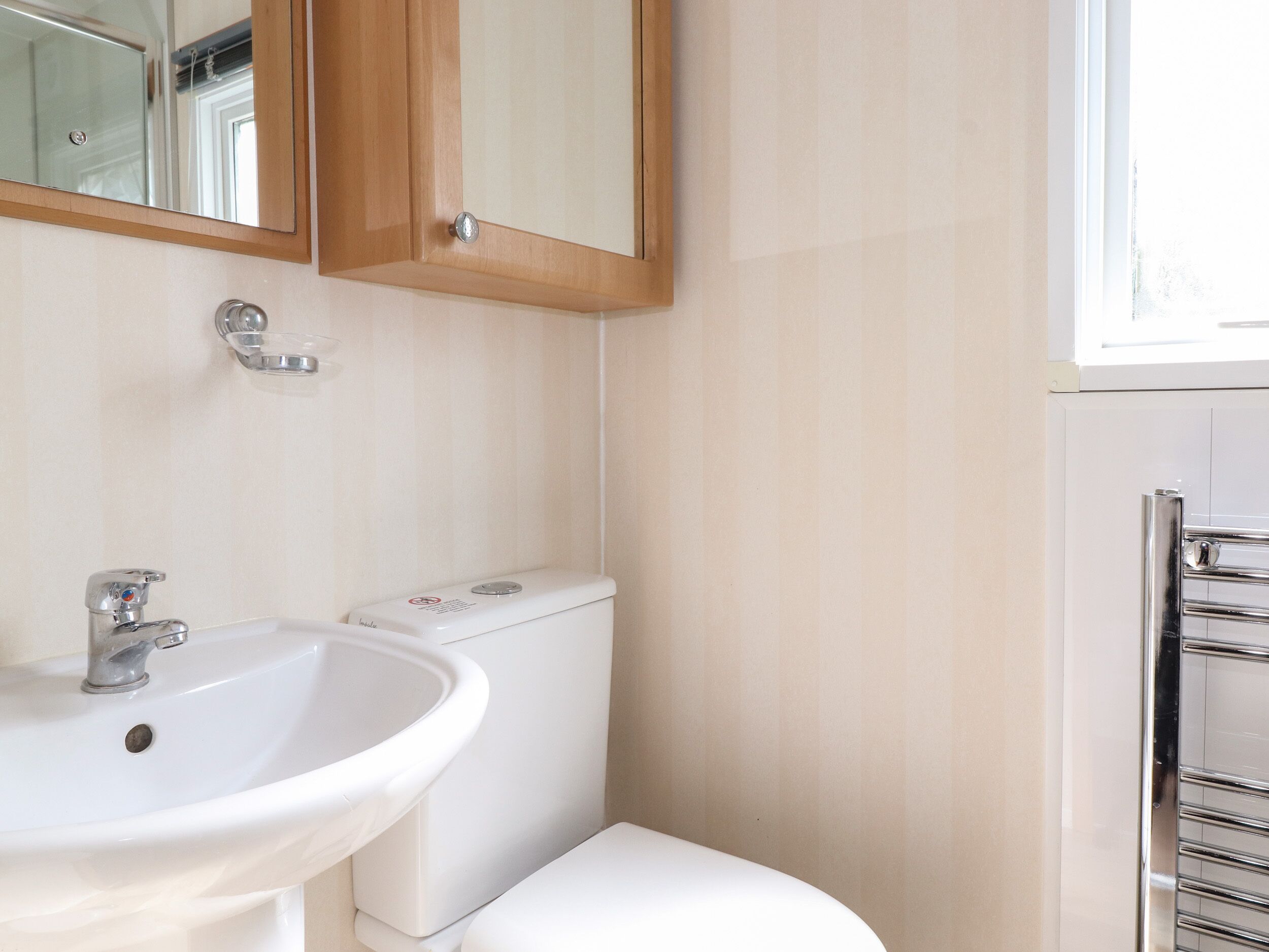 Een badkamer met een wit wastafelmeubel, een toilet en een spiegel boven de wastafel.