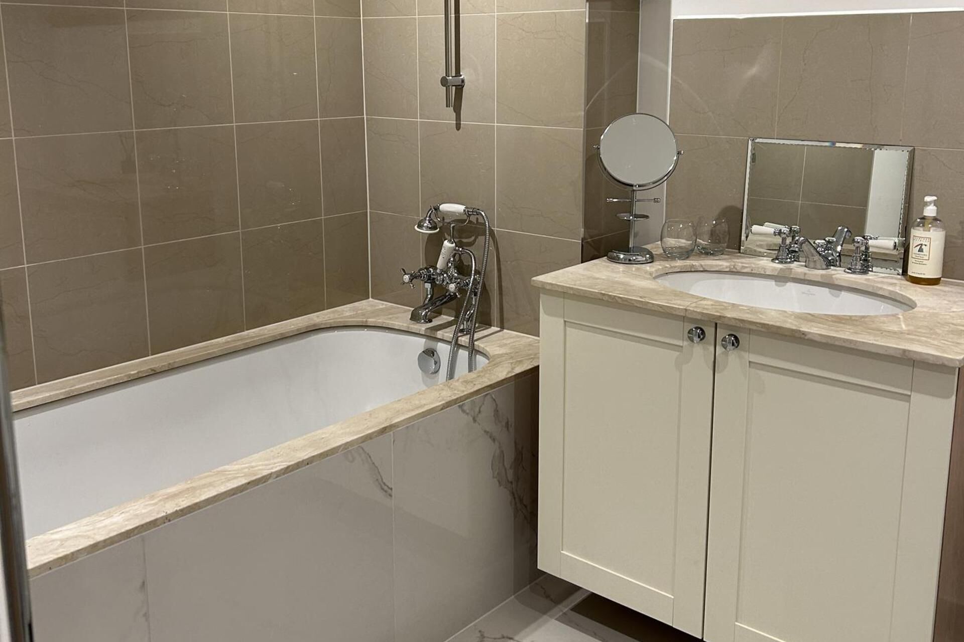 A modern bathroom with a freestanding bathtub, a double sink vanity, and a large mirror.