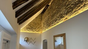 A room with a rustic ceiling, a wall-mounted light fixture, a mirror, and a wicker basket. - No Longer Available (Petworth)