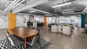 A modern office space with a large wooden conference table, gray chairs, and a mix of seating areas including sofas and a coffee table. - Centrally located - 2 min walk to UAB (Birmingham)