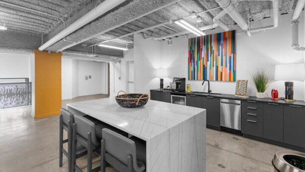 A modern kitchen with a central island, grey cabinets, and a colorful abstract painting on the wall. - Centrally located - 2 min walk to UAB (Birmingham)
