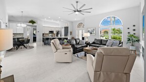 A spacious living area with a modern kitchen, a dining area, and a large window offering a view of the outdoors. - Relaxing Water views and close to dining, shopping and beaches (Cape Coral)