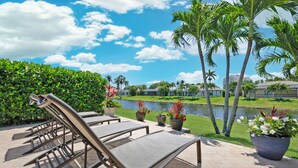 A patio area with lounge chairs, a water feature, and a view of a lake and buildings. - Relaxing Water views and close to dining, shopping and beaches (Cape Coral)