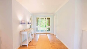 A hallway with a wooden floor, white walls, and a door leading outside. - Long Lane Stables Lodge. Spacious Country Retreat (Penselwood)