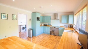 A modern kitchen with light blue cabinets, stainless steel appliances, and a wooden floor. - Long Lane Stables Lodge. Spacious Country Retreat (Penselwood)
