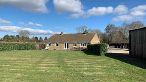 A single-story house with a well-maintained lawn and a wooden barn in the background. - Long Lane Stables Lodge. Spacious Country Retreat (Penselwood)