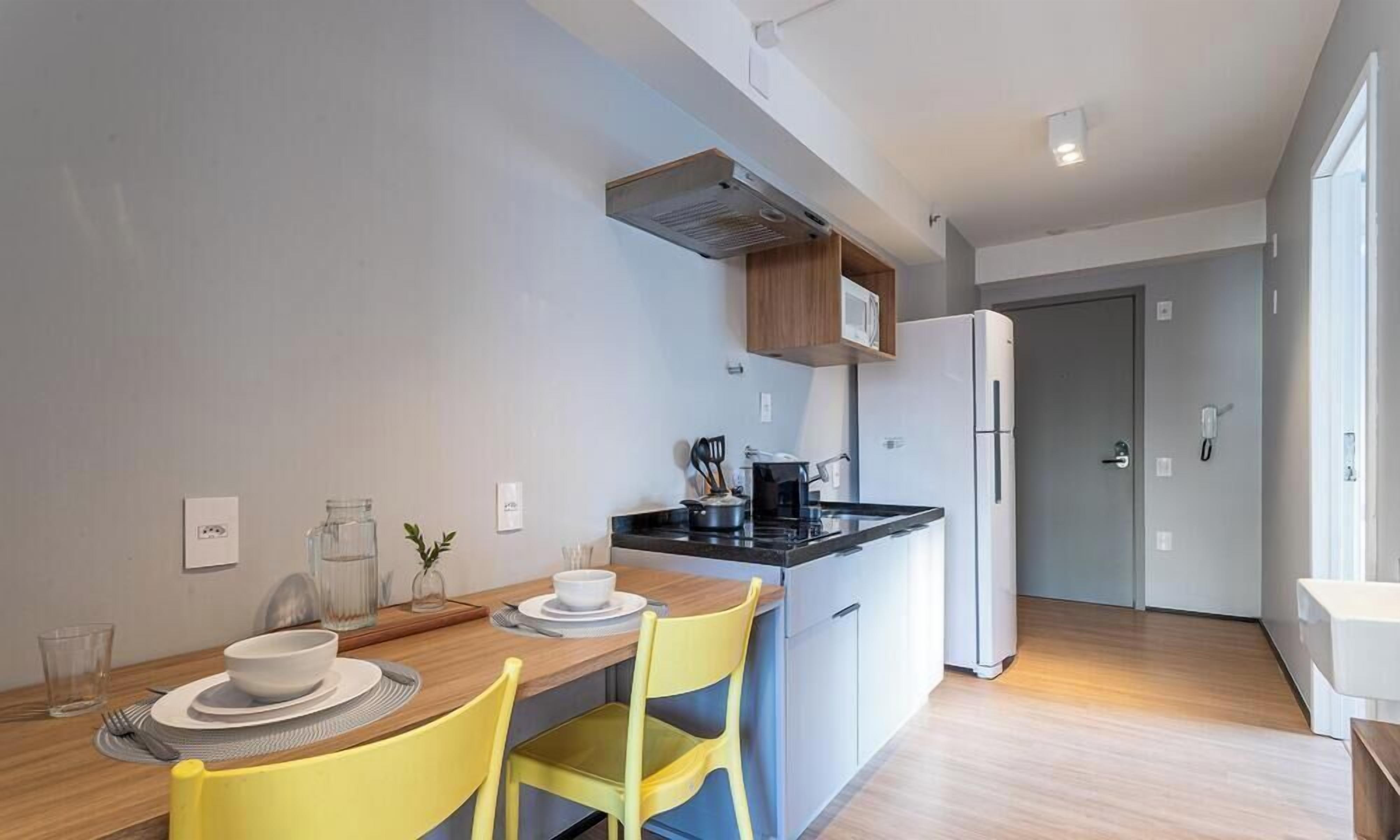 A modern kitchen with a dining table, chairs, a refrigerator, and a microwave.