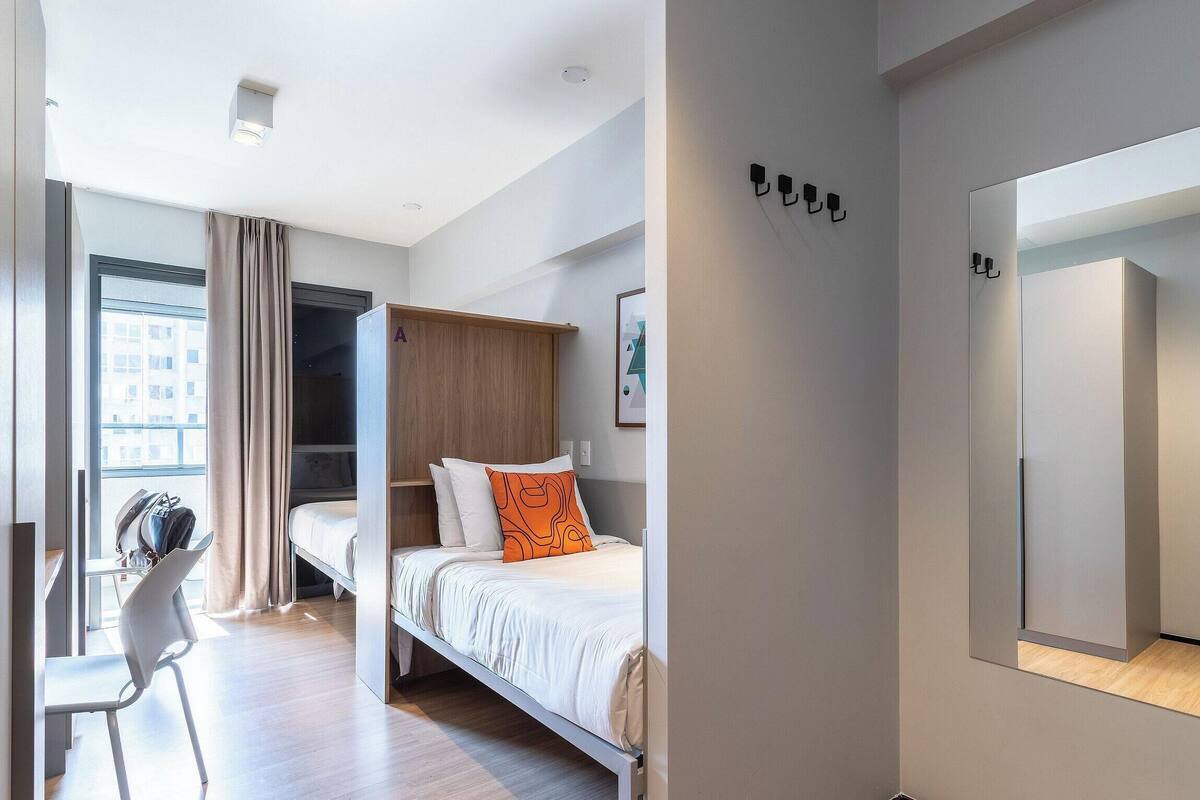 Ein modernes Hotelzimmer mit Bett, Schreibtisch und Kleiderschrank.