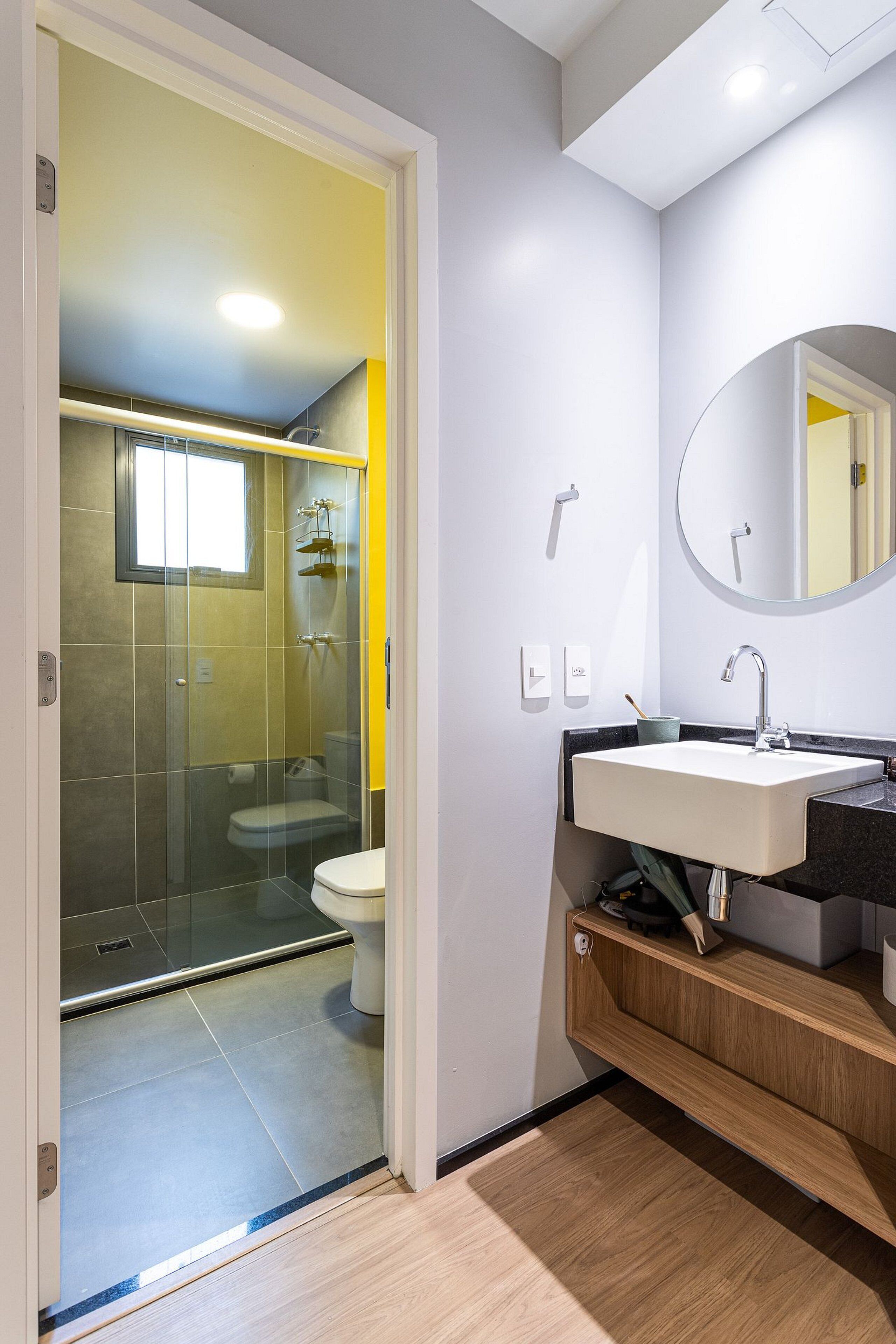 A modern bathroom with a glass shower enclosure, a white sink, and a mirror.