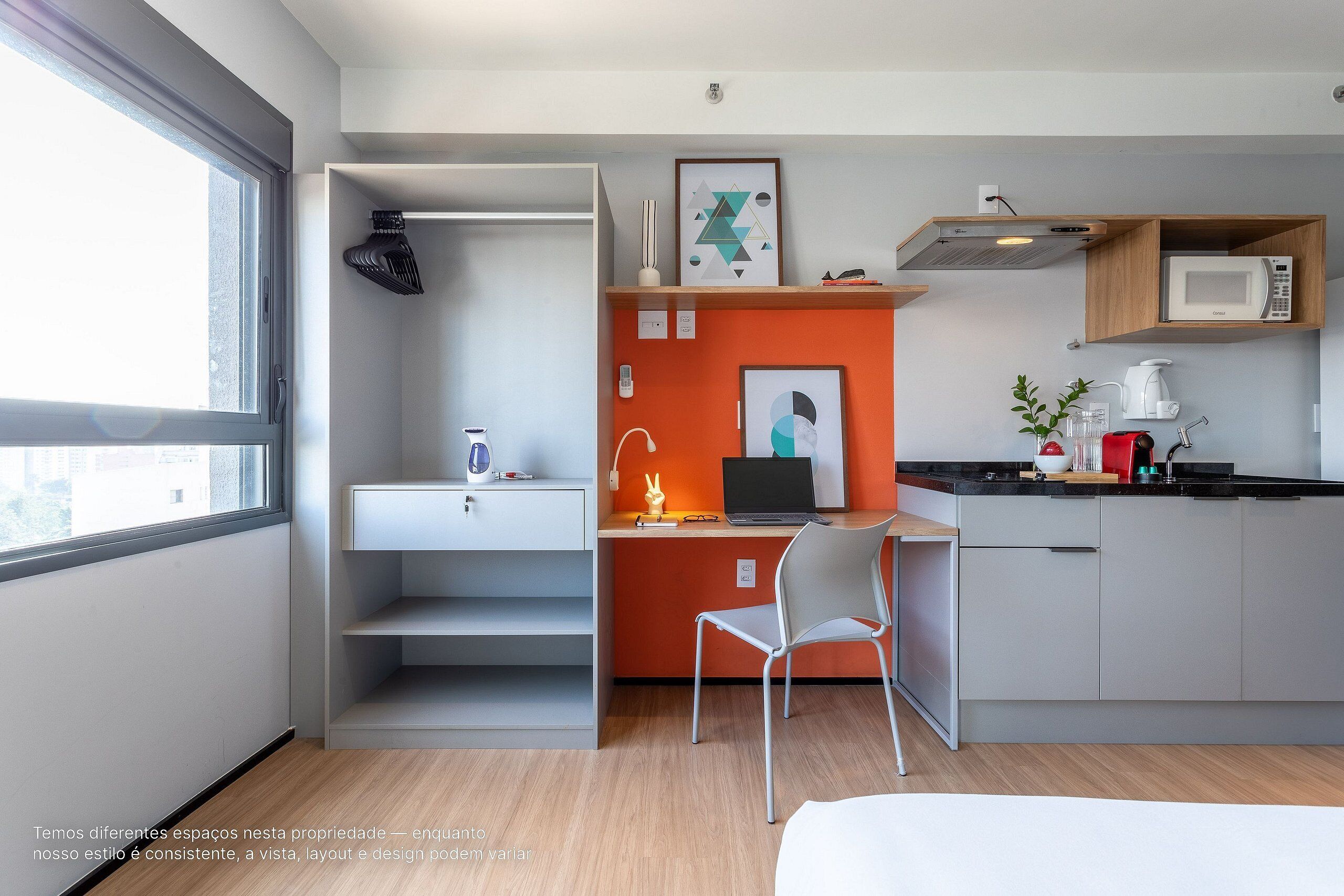 A modern kitchen with a microwave, coffee maker, and a laptop on the counter.