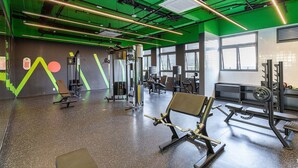 Une salle de sport équipée de matériel d’exercice, dotée de grandes fenêtres et d’un éclairage vert.