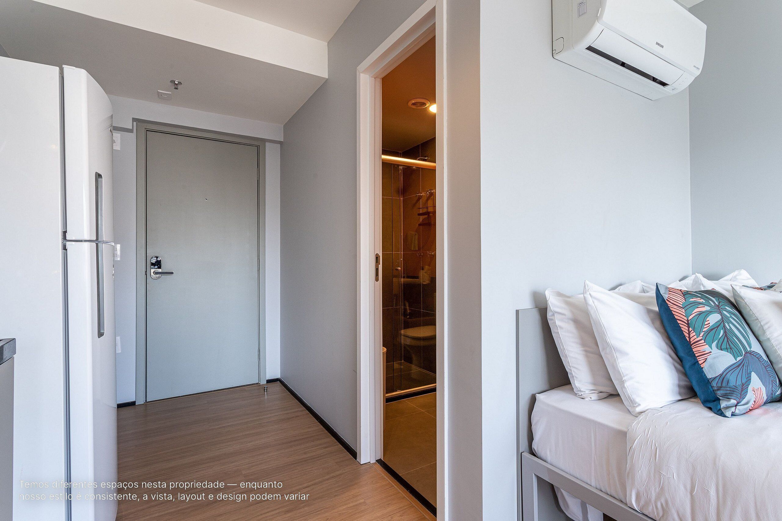 A modern bedroom with a bed, pillows, and an air conditioning unit.