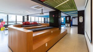 Un espace d’accueil moderne, doté d’un comptoir de réception en bois, de sièges et d’une grande fenêtre offrant une vue sur l’extérieur.