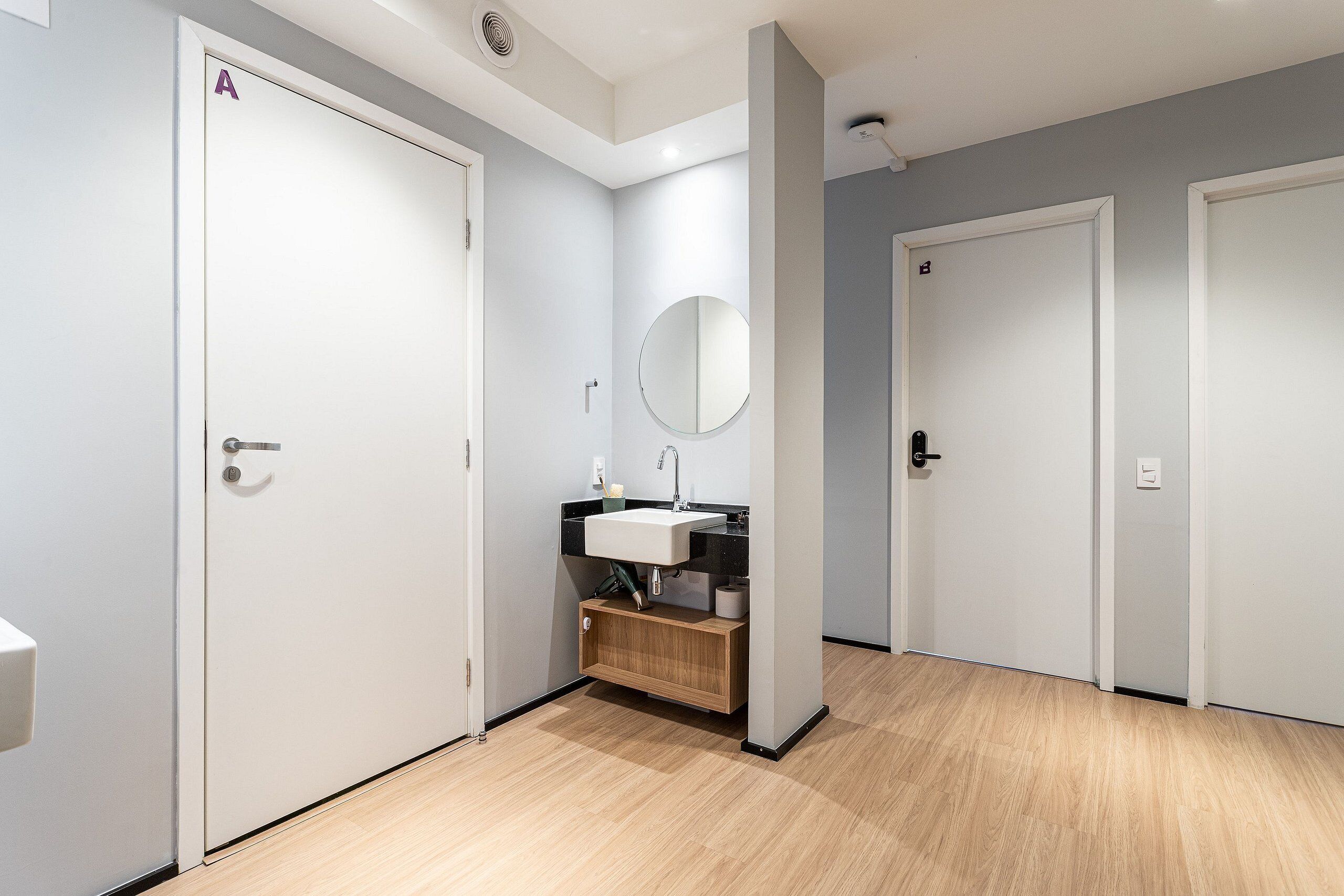 A modern bathroom with a sink, mirror, and wooden cabinet.