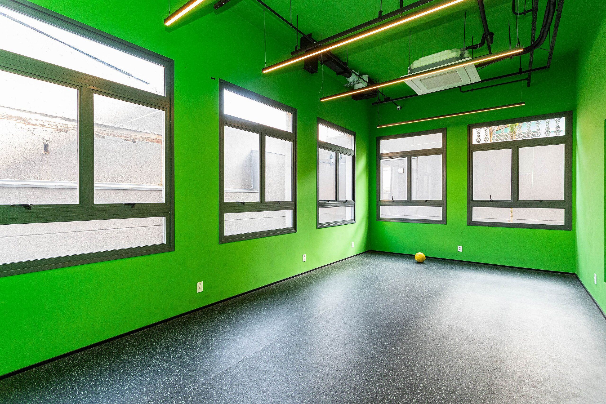 A room with green walls, large windows, and a black floor.