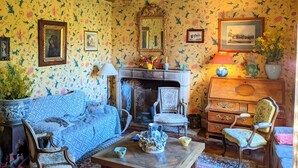 Una stanza accogliente con camino, carta da parati floreale e mobili d'epoca.