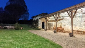 Un edificio in pietra con un patio coperto, posti a sedere all'aperto e un vialetto in ghiaia che conduce all'ingresso.