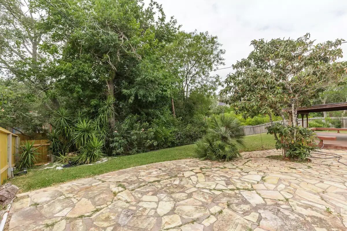 A stone patio surrounded by lush greenery and trees.
