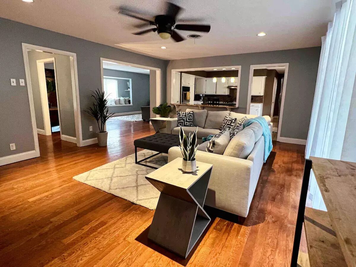 A spacious living room with hardwood flooring, a modern sofa, a coffee table, and a ceiling fan.
