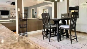 Cocina moderna con comedor, que incluye una isla central, sillas de madera oscura e iluminación colgante.