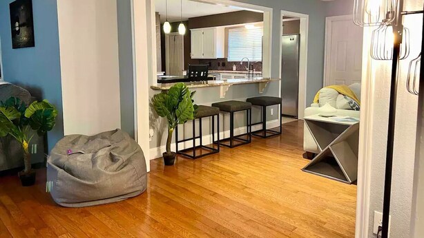 Una cocina moderna con suelo de madera, una zona con taburetes de bar y una mesa de comedor.