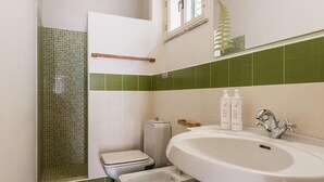 A bathroom with a shower, toilet, bidet, and sink.
