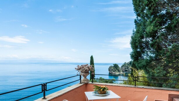 A terrace with a table and chairs overlooking a coastal view. - Casetta Amelia With Seaview by Wonderful Italy (Taormina)