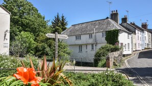 A quaint village street with a directional signpost, traditional buildings, and lush greenery. - 21 Mill Green (Lyme Regis)