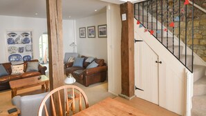 A living room with a wooden dining table, two sofas, and a staircase with heart decorations. - 21 Mill Green (Lyme Regis)