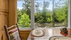 A wooden dining table with a view of a forested area through a window.