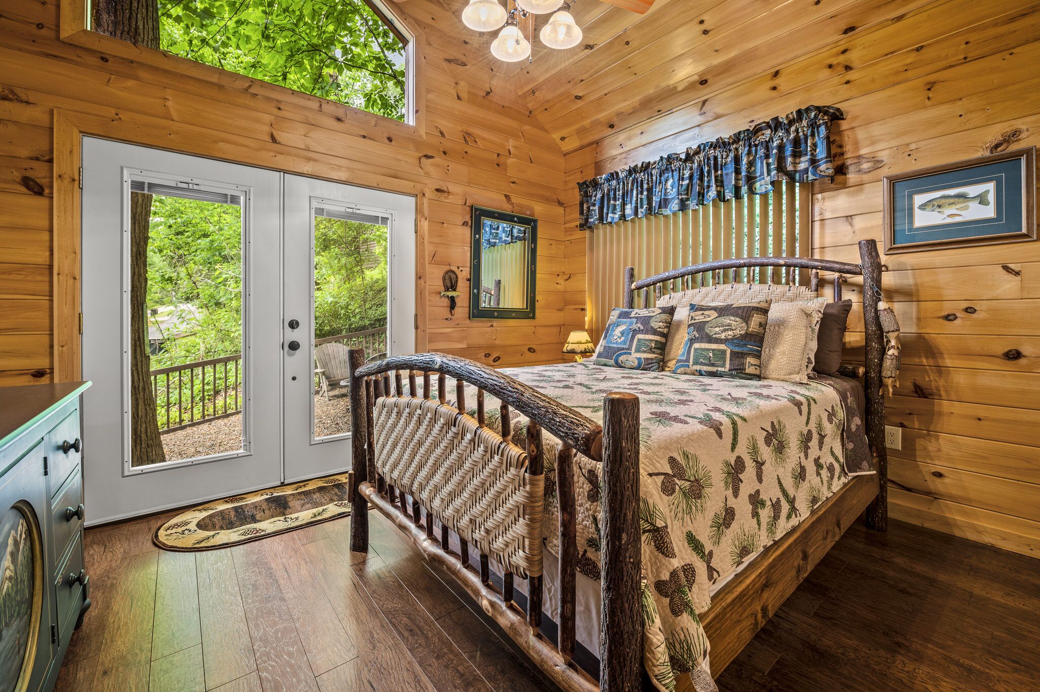 A wooden cabin bedroom with a bed, a dresser, and a door leading to a balcony.