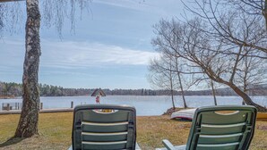 Deux chaises placées face à un lac, avec un quai et un bateau.