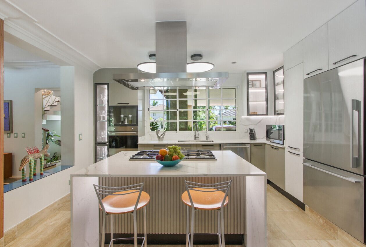 A modern kitchen with a central island, stainless steel appliances, and a view to the outdoors.