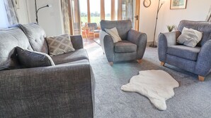 Una sala de estar acogedora con sofás grises, un sillón gris y una alfombra mullida blanca.