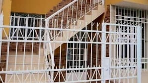 A staircase with white railings leading to a door with a metal gate. - Departamento Acogedor Ebenezer - Chincha (Chincha Alta)