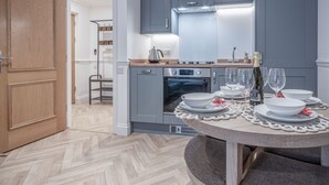 Uma cozinha moderna com armários cinzas, forno embutido e uma mesa de jantar posta com pratos e copos brancos.