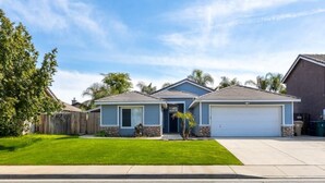 A two-story house with a garage, a well-maintained lawn, and a clear blue sky.