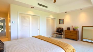 Une chambre à coucher comprenant un lit, une chaise, une commode, un miroir et un ventilateur de plafond.