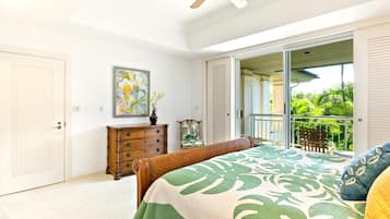 A bedroom with a bed, a dresser, a painting, and a sliding glass door leading to a balcony.