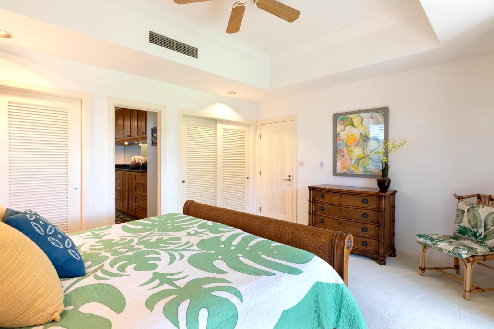 A bedroom with a bed, a dresser, a chair, and a ceiling fan.