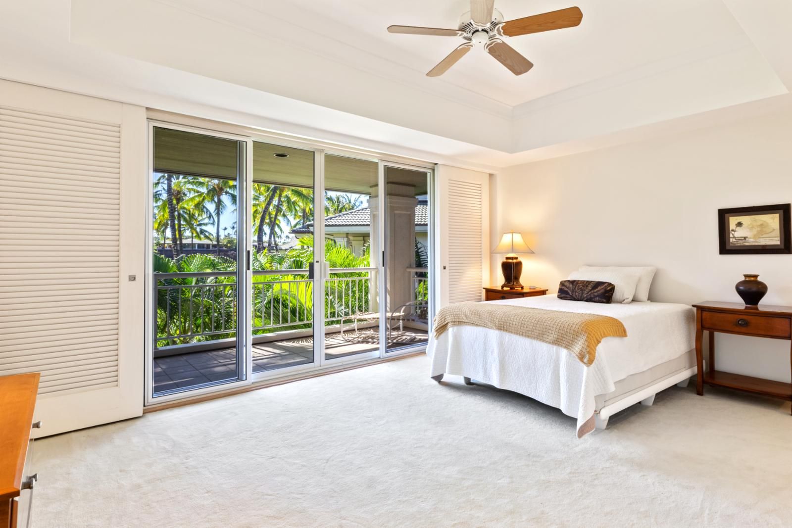 A bedroom with a bed, a nightstand, a lamp, and a ceiling fan.
