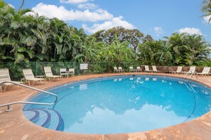 A swimming pool surrounded by lounge chairs and palm trees.