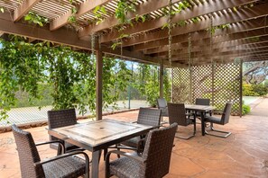 Eine Terrassenanlage im Freien mit Korbmöbeln und einer Pergola.