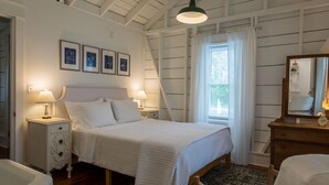 Un dormitorio con una cama, dos mesitas de noche con lámparas, un aparador, un espejo y cuadros en la pared.
